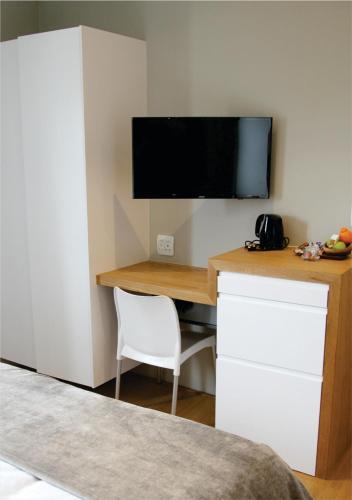 a room with a desk with a television on a wall at Oceans Guest House & Luxurious Apartments in Struisbaai