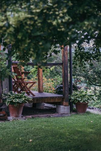a wooden bench in a park with two potted plants at Mala Kmetija in Slovenske Konjice