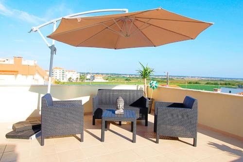 a patio with two chairs and an umbrella at RiaMar - Praia da Vagueira in Gafanha da Vagueira