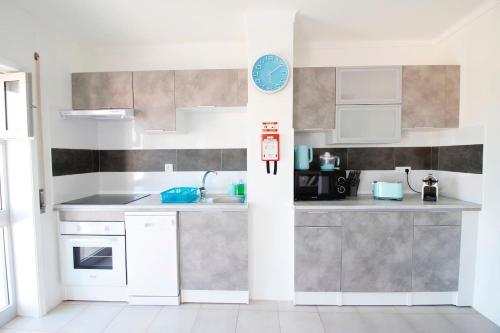 a kitchen with white cabinets and a blue clock on the wall at RiaMar - Praia da Vagueira in Gafanha da Vagueira