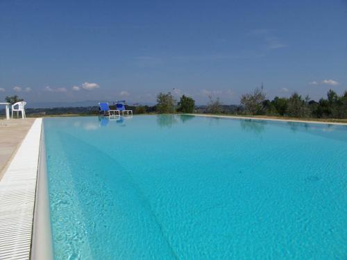 a large swimming pool with blue water at AGRITURISMO SANTA BARBARA COUNTRY HOUSE in San Miniato