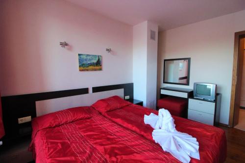 a bedroom with a red bed and a television at Mountview Lodge Apartments in Bansko