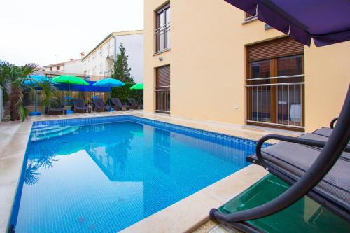 uma piscina com uma cadeira ao lado de um edifício em Apartments Jukić em Porec