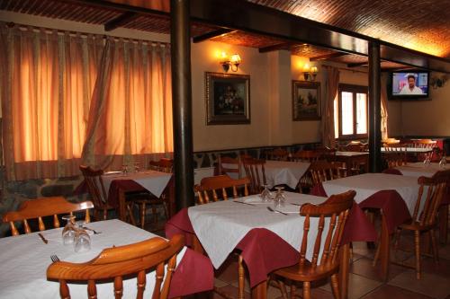 a restaurant with white tables and chairs and a tv at Venta El Laminador in Riópar