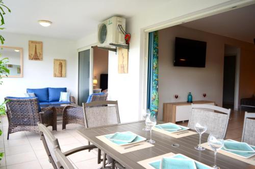 - une salle à manger et un salon avec une table et des chaises dans l'établissement Kai cosy apartment with terrace pool and sea view near Papeete, à Fa'a'ā