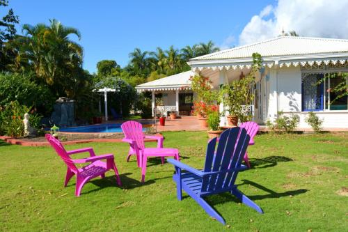 four colorful chairs sitting in the grass in front of a house at Villa Tangara - Faa'a - Tahiti - 3 bedrooms - pool and lagon view - 6 pers in Faaa