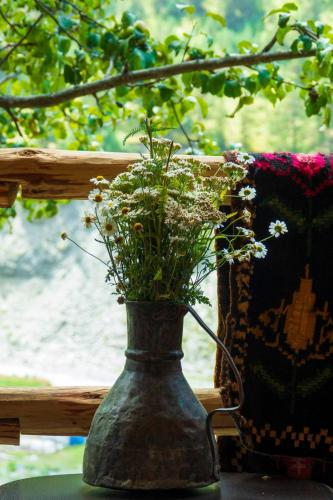 a vase with flowers in it next to a window at Pirikiti in Akhmety