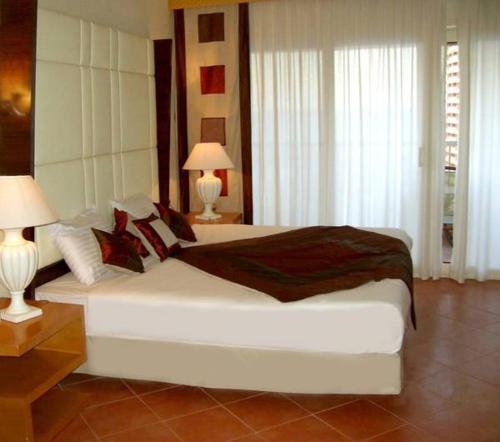 a bedroom with a large white bed with two lamps at Chalet in Pyramids Porto Sokhna in Ain Sokhna
