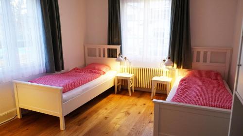 two beds in a bedroom with two windows at Adventure Guesthouse Interlaken in Interlaken