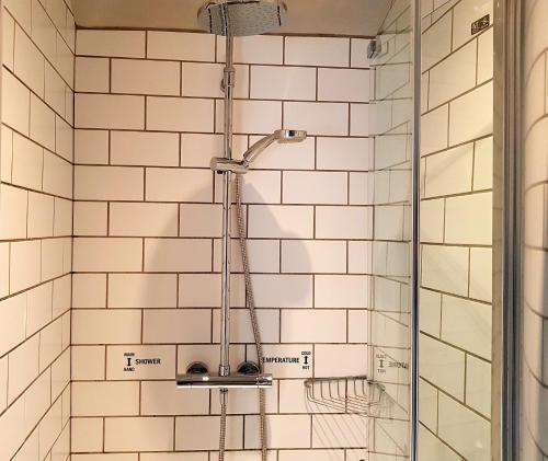 a shower in a bathroom with white tiled walls at The Carpenters Arms in Pensford