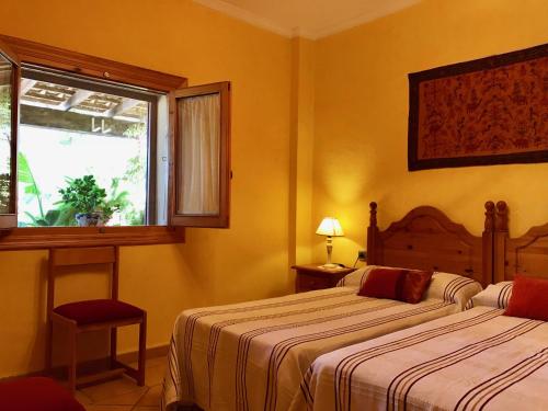 Habitación de hotel con 2 camas y ventana en Casa Rural LOS CORTESES, en Los Díaz