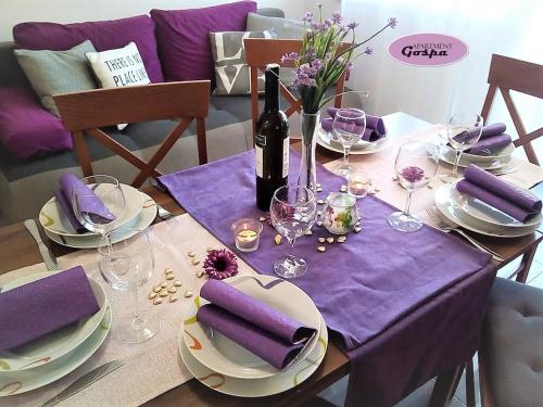 einen Tisch mit einem lila Tischtuch und einer Flasche Wein in der Unterkunft Apartment Gospa in Pula