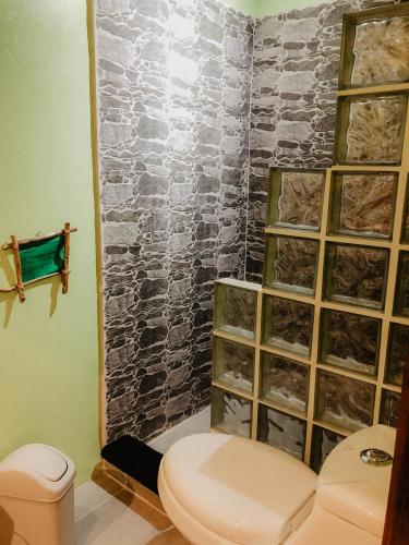 a bathroom with a toilet and a stone wall at Samara Chillout Lodge - Adults only in Sámara