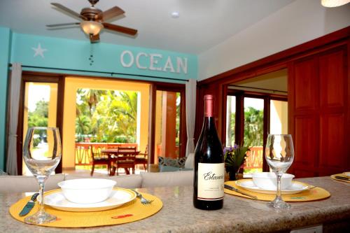 a bottle of wine sitting on a table with two glasses at The Villas at Cocoplum in Placencia Village