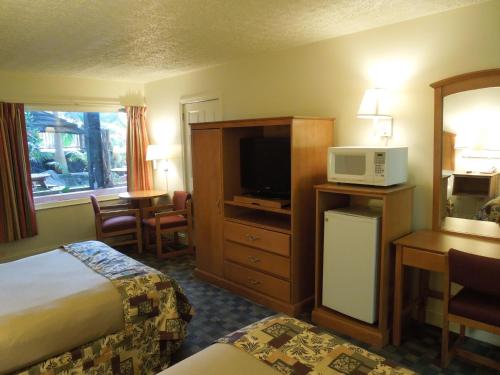 a hotel room with a bed and a television at Wildwood Inn in Florence