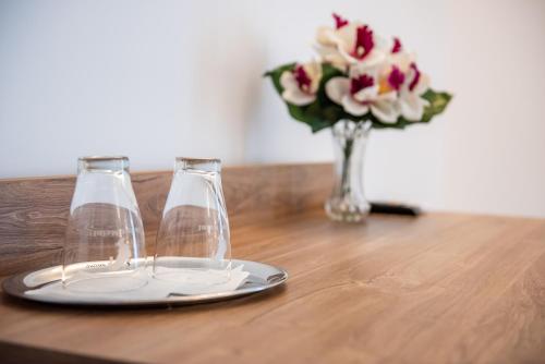 a table with two wine glasses and a vase of flowers at Pensiunea Carul cu flori in Oraviţa