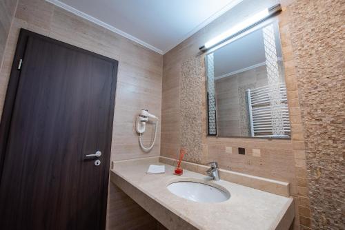 a bathroom with a sink and a brown door at Pensiunea Carul cu flori in Oraviţa