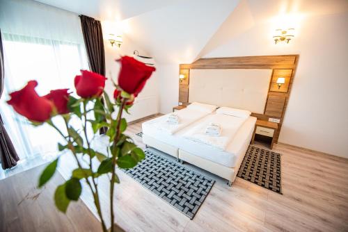 ein Schlafzimmer mit einem Bett und einer Vase aus Rosen in der Unterkunft Pensiunea Carul cu flori in Oraviţa