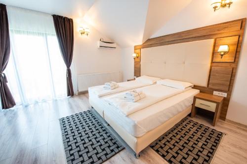 a bedroom with a large bed and a large window at Pensiunea Carul cu flori in Oraviţa