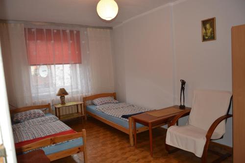 a bedroom with two beds and a chair and a table at Mieszkanie Tolkmicko in Tolkmicko