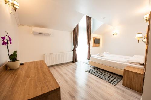 a bedroom with a bed and a wooden table at Pensiunea Carul cu flori in Oraviţa