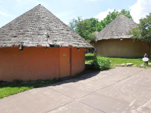 two huts with thatched roofs and a sidewalk at Wildwood Inn in Florence