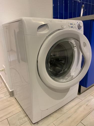 uma máquina de lavar roupa branca numa casa de banho com paredes azuis em Otto - Bilocale ad Alassio em Alassio