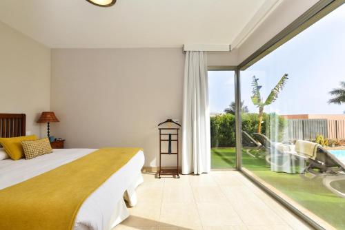 une chambre avec un lit et une grande fenêtre en verre dans l'établissement Salobre Villa with Pool Par 4 nr 9 by VillaGranCanaria, à Salobre