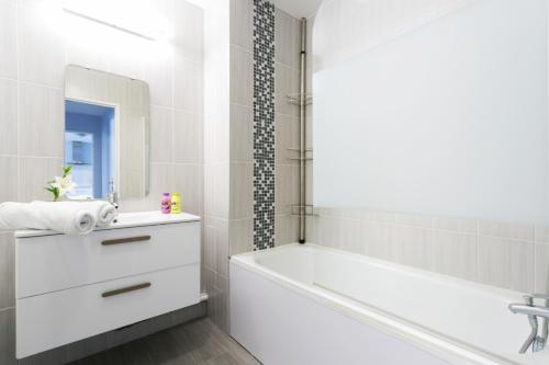 Un baño blanco con bañera y lavabo. en Dream destination, en Montévrain