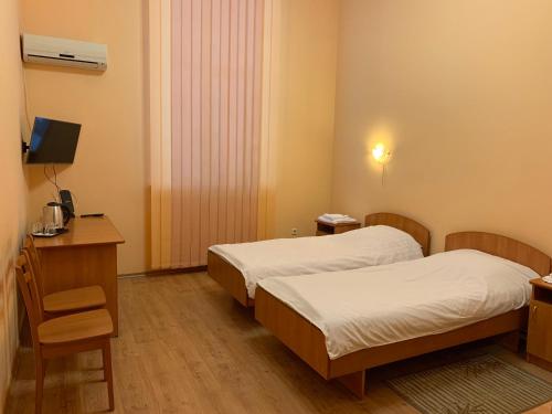 キーウにあるInn on Zhytomyrskaのベッド2台、デスク、テレビが備わる客室です。