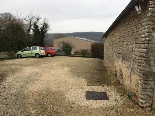 two cars parked in a driveway next to a brick wall at Chambre du verger in Francheville