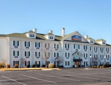 un grande edificio bianco con parcheggio di Howard Johnson by Wyndham Jackson a Jackson