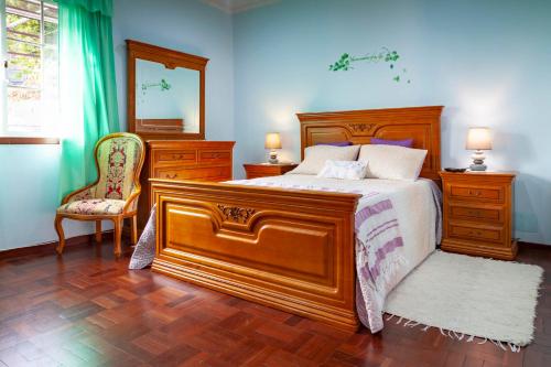 a bedroom with a large wooden bed and a chair at Casa da Maria 15 - Funchal - Famílias in Funchal