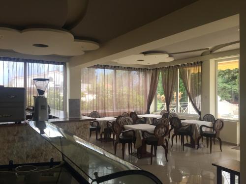 a restaurant with tables and chairs and large windows at Galini in Loutra Edipsou
