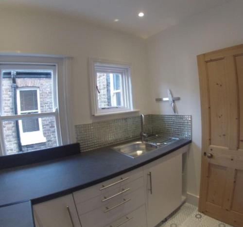 a kitchen with a counter and a sink and two windows at Park View - Two bedroom apartment in Worthing