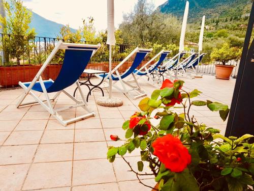 a row of blue chairs and a table on a patio at Villa Belvedere Hotel in Limone sul Garda
