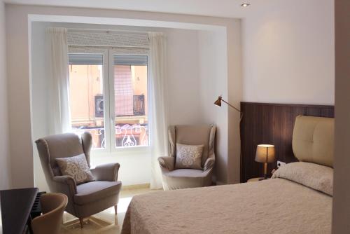 ein Schlafzimmer mit 2 Stühlen, einem Bett und einem Fenster in der Unterkunft Valencia Town Center New Apartments in Valencia