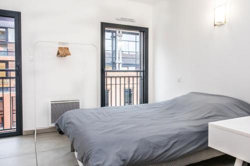 um quarto com uma cama e uma grande janela em 202 - Appartement Duplex Moderne - Jeanne d'Arc, Toulouse em Toulouse