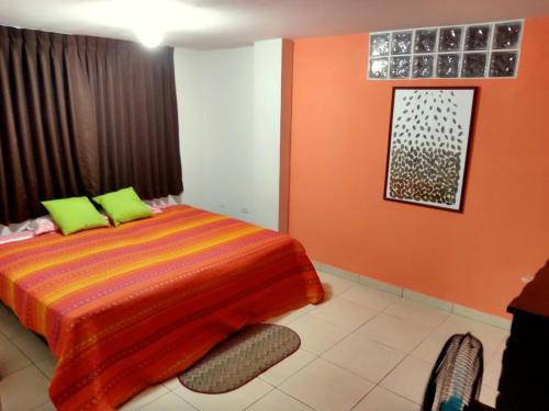 Schlafzimmer mit orangefarbenen Wänden und einem Bett mit grünen Kissen in der Unterkunft La Casa del Che Fernando in Lima