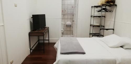 a white bedroom with a bed and a television at Casa Mayela Guest House in San José