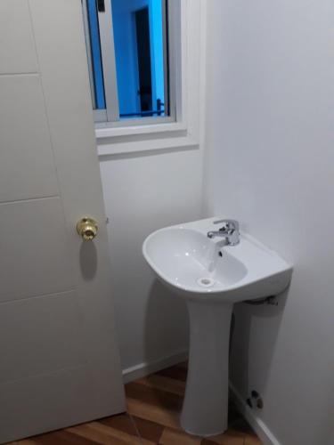 baño con lavabo blanco y ventana en Hostal Alessandri, en Curicó