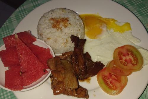 a plate of breakfast food with eggs meat and rice at Prince Transient house in San Jose