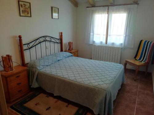 a bedroom with a bed and a chair and a window at Las Casonas de Chavida in Chavida