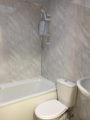 a bathroom with a toilet and a tub and a sink at Sama's Stylish Room 3 in Manchester
