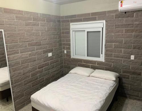 a bed in a room with a brick wall at Residencial Infinito - Praia de Palmas in Governador Celso Ramos