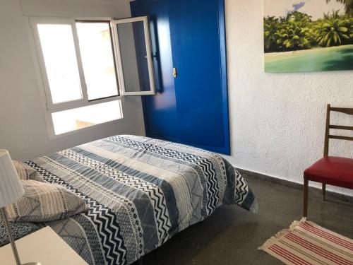 ファロ・デ・クリェラにあるFantástico apartamento en Faro de Culleraのベッドルーム1室(ベッド1台、窓、椅子付)