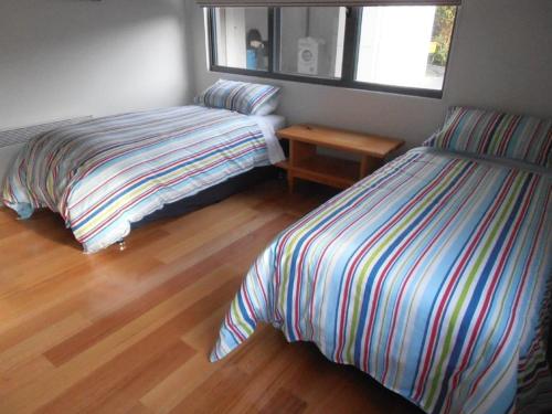 a bedroom with two beds and a wooden floor at Gull Apartment in Strahan