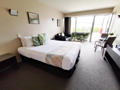Habitación de hotel con cama grande y balcón. en Belmont Motor Inn, en Christchurch