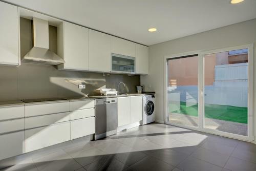 a kitchen with white cabinets and a dishwasher at Summer holiday in Fernao Ferro