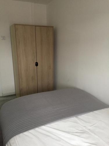 a bedroom with a bed and a wooden cabinet at Sama's Stylish Room 2 in Manchester